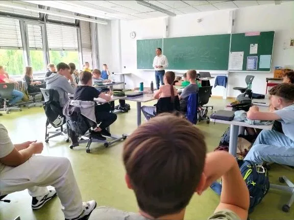A teacher leading a class while students work at their tables